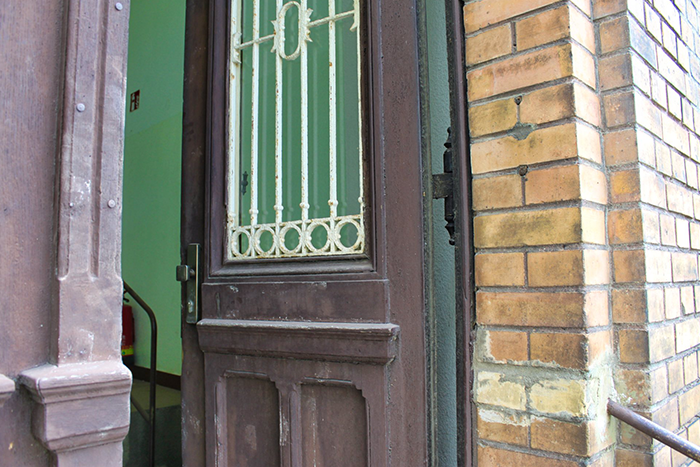 Offen stehende Holztür zu einem grün gestrichenen Hauseingang